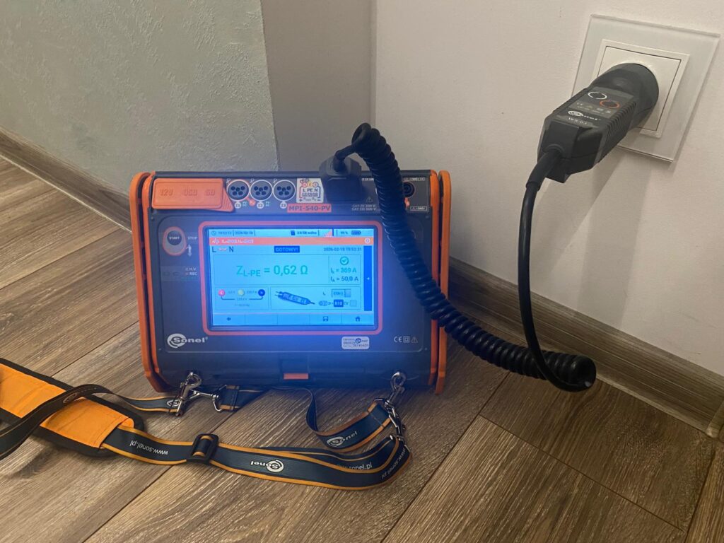 Pomiary elektryczne instalacji w domu – miernik podczas badania impedancji pętli zwarcia w gniazdku
