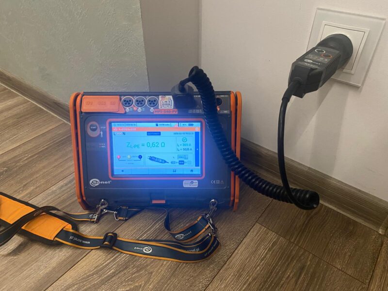 Pomiary elektryczne instalacji w domu – miernik podczas badania impedancji pętli zwarcia w gniazdku