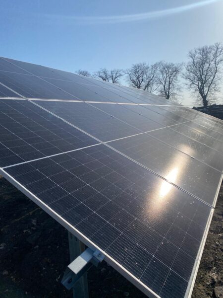 Panele fotowoltaiczne zamontowane na konstrukcji gruntowej przy domu jednorodzinnym