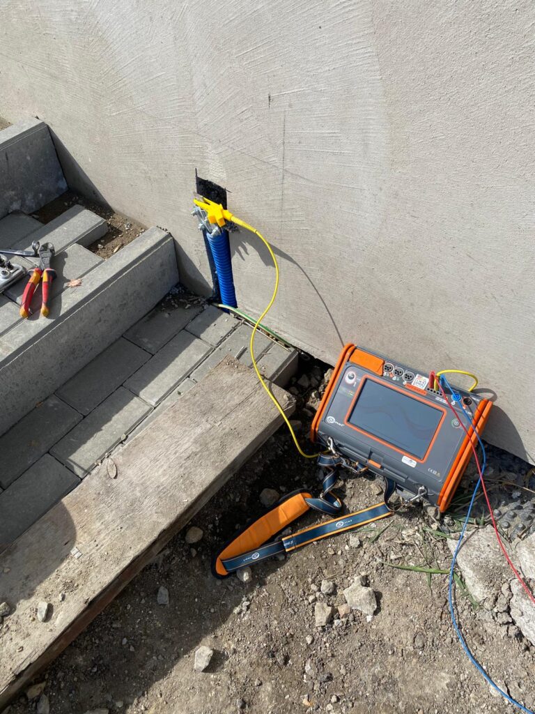 Pomiary elektryczne Miernik do pomiaru uziemienia podłączony do instalacji przy budynku
