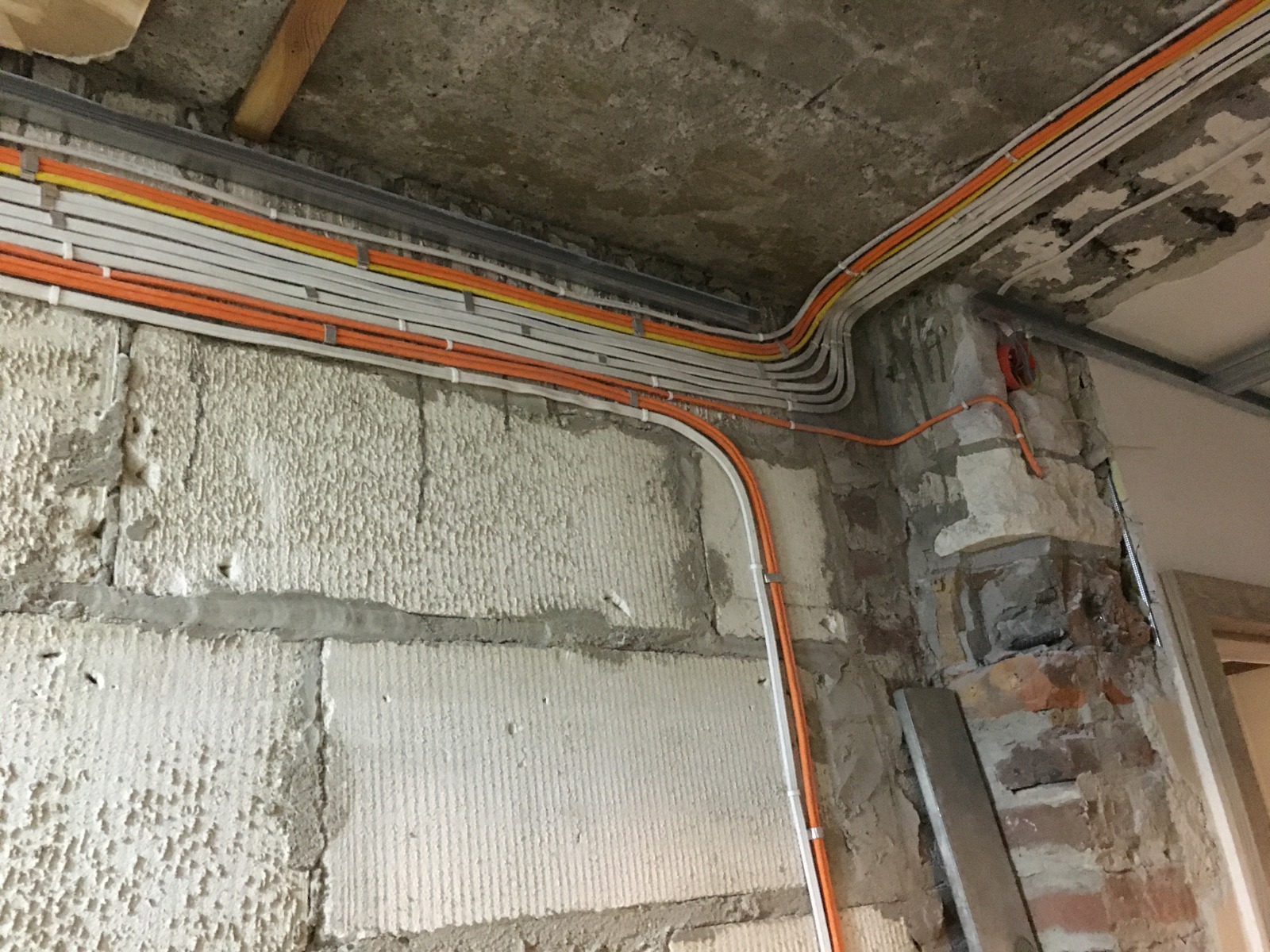 Przewody elektryczne prowadzone w rurkach instalacyjnych na ścianie i suficie w budynku